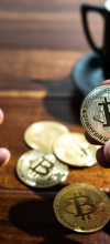 img:Bitcoins físicos junto a smartphone com gráfico de mercado, simbolizando soberania digital e investimento em Bitcoins